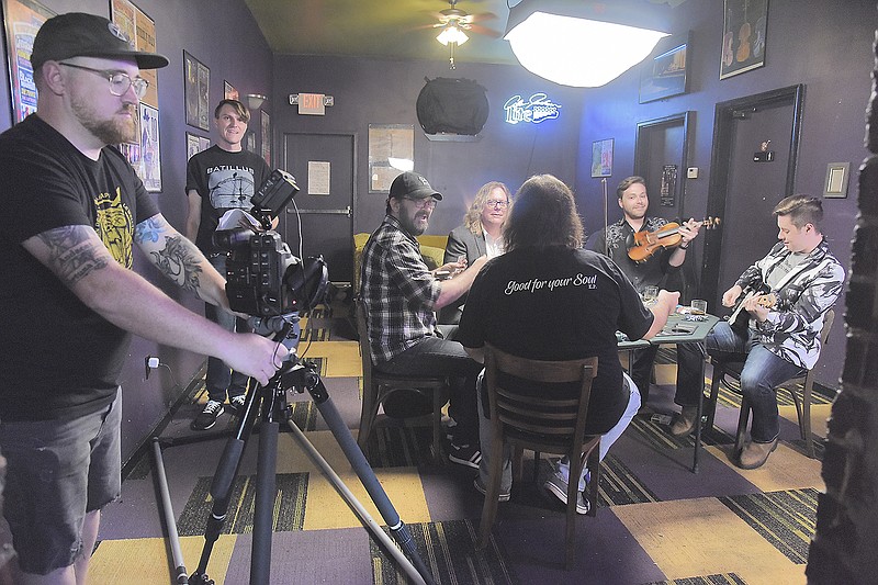 Producer and Director Jim Turner, second from left, watches the scene play out Monday on the small monitor as Jay Pelzer, of Tag Productions, at left, rolls his camera on a rail for smooth video scenes. Both were at The Mission to shoot scenes for a music video featuring the music of Ray Cardwell, fourth from left. The song is titled "New Set of Problems." Featured in the video are, clockwise from left, Stephen Erangey, Cardwell, David Mansfield, Kelsey Krews and Rob Frommel. Mansfield and Krews are bandmates of Cardwell from Nashville, Tennessee.