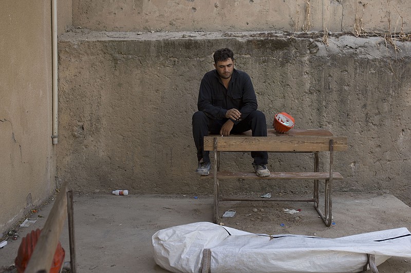 In this Saturday, Sept. 7, 2019 photo, a first responders takes a break after removing a body at the site of a mass grave in Raqqa, Syria. First responders say they have pulled nearly 20 bodies out of the latest mass grave uncovered in Raqqa, the Syrian city that was the de facto capital of the Islamic State group. It is the 16th mass grave in the city, and officials are struggling with a lack of resources needed to document and one day identify the thousands of dead who have been dug out. (AP Photo/Maya Alleruzzo)