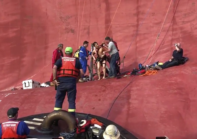 In this image taken from U.S. Coast Guard video on Monday, Sept. 9, 2019, a crew member of a capsized cargo ship is pulled from the vessel by Coast Guard rescuers off Jekyll Island, Ga. Coast Guard rescuers pulled four trapped men alive from the ship Monday, drilling into the hull's steel plates to extract the crew members more than a day after their vessel overturned while leaving a Georgia port. (U.S. Coast Guard via AP)