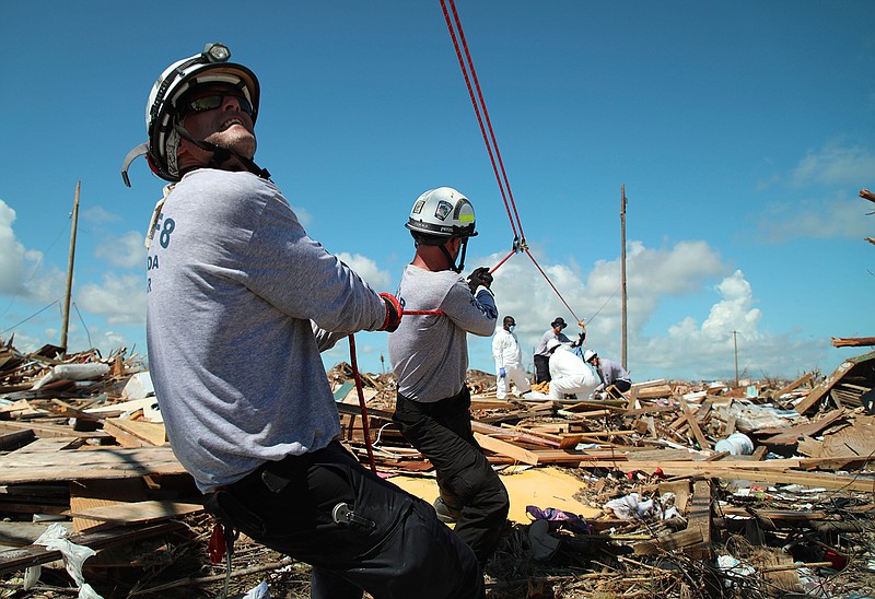 Members of the fire rescue team Task Force 8, from Gainesville, Florida, help remove a body one week after Hurricane Dorian hit The Mudd neighborhood in the Marsh Harbor area of Abaco Island, Bahamas, Monday, Sept. 9, 2019. Dorian, the most powerful hurricane in the northwestern Bahamas' recorded history, has killed at least 44 people in Bahamas as of Sunday, Sept. 8, according to the government.  (AP Photo/Gonzalo Gaudenzi)