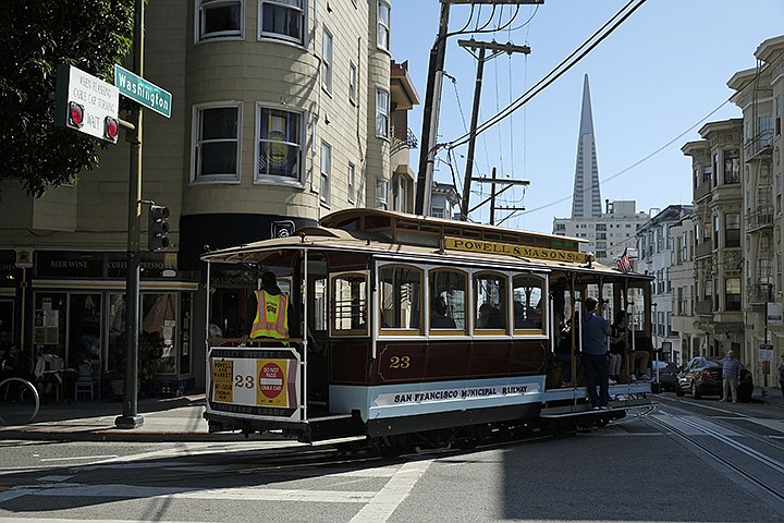 A cable car turns onto Washington Street with the Transamerica Pyramid in the background Wednesday, Sept. 11, 2019, in San Francisco. San Francisco's iconic cable cars will stop running for 10 days starting Friday to undergo repairs. The city's transit agency says it needs to get the manually operated cable cars off the street to rehabilitate the gearboxes that power the system that started in the 1890s. Shuttle buses will instead transport people along the steep streets of the cable car routes. (AP Photo/Eric Risberg)