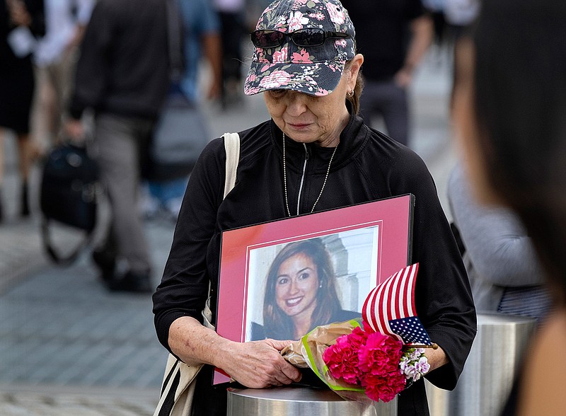 Connie Dray of West Virginia holds a photo Wednesday, Sept. 11, 2019, of her cousin Mary Lou Hague, who died in the World Trade Center attacks of Sept. 11, 2001, as she stands near One World Trade Center while ceremonies marking the 18th anniversary were underway nearby. This was Dray's first time at the ceremonies, saying it was on her list of important things to accomplish, as she also close with Hague's family. (AP Photo/Craig Ruttle)