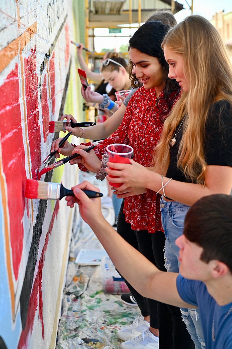 Pleasant Grove High School art students paint on the Dr Pepper mural after learning the process of painting a mural from David Freeman on Wednesday in Texarkana, Arkansas. The mural is on the side of TLC Burgers and Fries in the downtown area. It will be unveiled on Oct. 4, in conjunction with Dine on the Line. 
