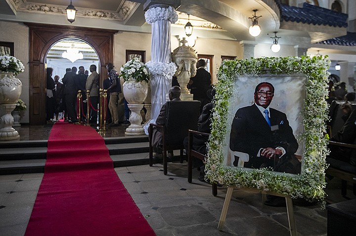 A portrait of former president Robert Mugabe stands outside the room where his body lies in state inside his official residence in the capital Harare, Zimbabwe Wednesday, Sept. 11, 2019. Zimbabwe's founding leader Robert Mugabe made his final journey back to the country Wednesday, his body flown into the capital amid the contradictions of his long, controversial rule. (AP Photo/Ben Curtis)