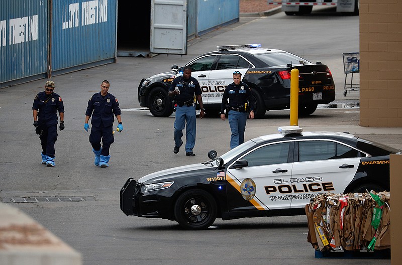 In this Aug. 6, 2019, file photo, police officers walk behind a Walmart at the scene of a mass shooting at a shopping complex in El Paso, Texas. Patrick Crusius, 21, was indicted Thursday, Sept. 12, 2019, for capital murder in connection with the Aug. 3 mass shooting that left 22 dead. He is jailed without bond. (AP Photo/John Locher, File)