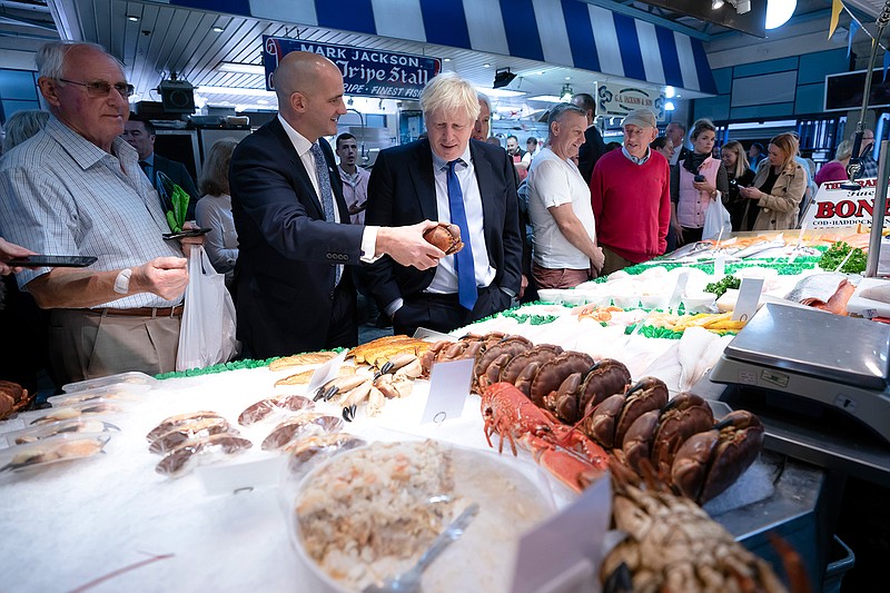 Britain's Prime Minister Boris Johnson, center left, speaks with Northern Powerhouse minister Jake Berry, second left, as they stop at a fishmongers  during a visit to Doncaster Market, in Doncaster, Northern England, Friday Sept. 13, 2019. Johnson will meet with European Commission president Jean-Claude Juncker for Brexit talks Monday in Luxembourg. The Brexit negotiations have produced few signs of progress as the Oct. 31 deadline for Britain's departure from the European Union bloc nears. ( AP Photo/Jon Super)