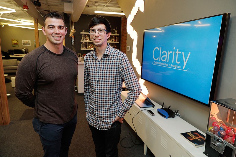 In this Tuesday, Sept. 10, 2019, photo Shane Griffiths, right, and Trenton Erker, left, co-owners of the digital marketing company Clarity Online, pose for a photo in Seattle. Griffiths and Erker use technology for tasks like billing, scheduling appointments, tracking the time they spend on clients' projects and putting together reports on visits to client websites, as well as using freelancers for other tasks as ways to save money on employment costs, and also have more flexibility when they need specific talents or expertise for a project. (AP Photo/Ted S. Warren)