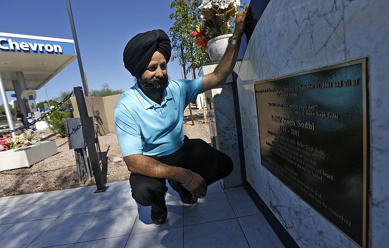 FILE - In this Aug. 19, 2016, file photo, Indian Sikh immigrant Rana Singh Sodhi kneels next to a memorial in Mesa, Ariz., for his murdered brother, Balbir Singh Sodhi, who was gunned down at the site four days after the Sept. 11, 2001 attacks by a man who mistook him for a Muslim because of his turban and beard. Sodhi has preached a message of peace and tolerance in hopes of helping others better understand his religion, the fifth largest in the world with some 25 million adherents including a half-million in the United States. (AP Photo/Ross D. Franklin, File)