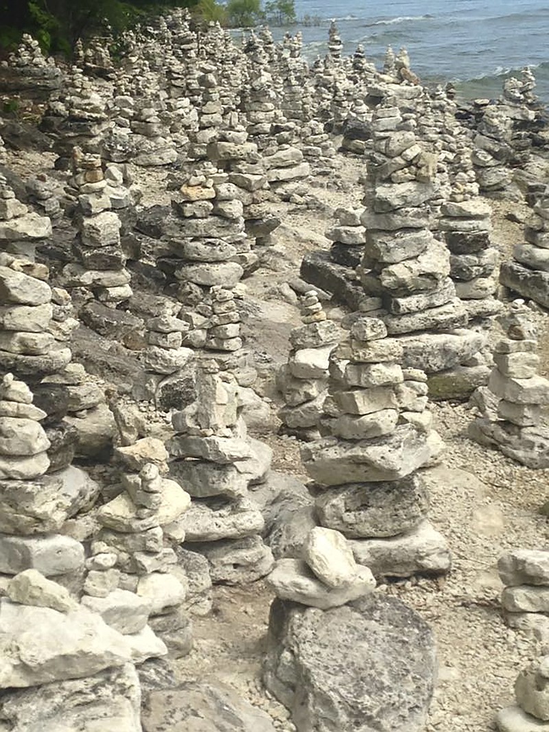 In this July 20, 2015 photo, numerous cairns stacked at Cave Point County Park are seen on the Lake Michigan shoreline in Door County, Wis.  To some along the north shoreline of Lake Superior in Minnesota, building stacks of rocks, or cairns, is akin to making sand castles and can even be meditative. To others, these manmade rock formations despoil nature's beauty and stand as monuments to the human ego.(AP Photo/Roger Schneider)