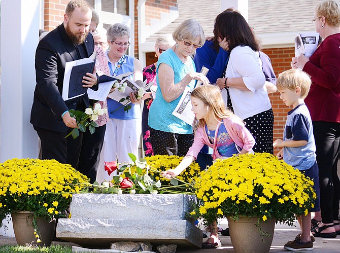 Rachel Smith, 8, of Etterville, places a red rose on top of the memorial stone Saturday during the seventh annual National Day of Remembrance for Aborted Children at St. Andrew Church in Holts Summit. The service was organized by three national pro-life groups: Citizens for a Pro-Life Society, Priests for Life and the Pro-Life Action League.