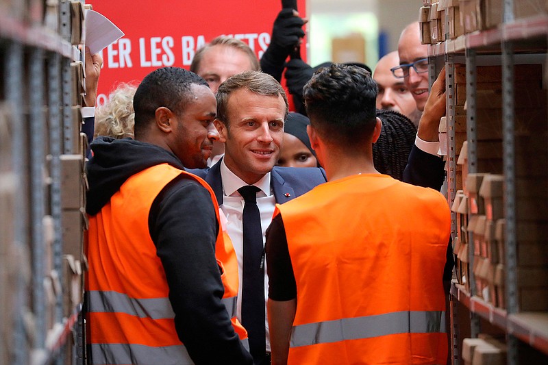 In this photo taken on Tuesday Sept. 10, 2019 French President Emmanuel Macron listens to warehouse workers in Bonneuil-sur-Marne, southwest of Paris. French President Emmanuel Macron was a world away from the glamor of hosting world leaders at a G-7 summit a few weeks earlier. This time, those he was trying to win over weren't President Donald Trump and other heads of states in the luxurious seaside resort of Biarritz, but workers struggling to make ends meet. (Ludovic Marin, Pool via AP)