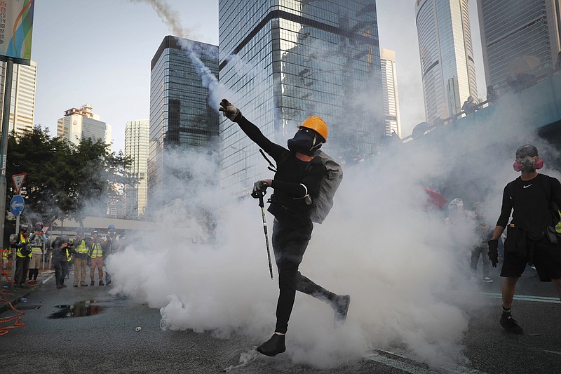 An anti-government protester throws back a tear gas canister fired by the police during a demonstration near Central Government Complex in Hong Kong, Sunday, Sept. 15, 2019. Police fired a water cannon and tear gas at protesters who lobbed Molotov cocktails outside the Hong Kong government office complex Sunday, as violence flared anew after thousands of pro-democracy supporters marched through downtown in defiance of a police ban. (AP Photo/Kin Cheung)