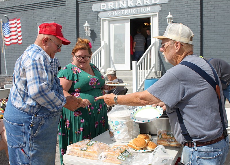 <p>Democrat photo/Liz Morales</p><p>David Bledsoe readies a plate of hamburgers and hot dogs Friday for Elizabeth Batye and Wayne Hagemeyer at the Get It, LLC open house and appreciation lunch at Drinkard Construction.</p>