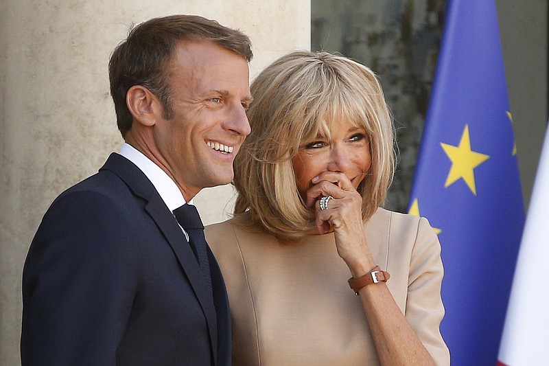 FILE - In this Thursday, Aug. 22, 2019 file photo, French President Emmanuel Macron, and his wife Brigitte, share a laugh as they wait for Greece's Prime Minister Kyriakos Mitsotakis at the Elysee Palace, in Paris. World leaders have offered support to Brigitte Macron, the wife of France’s president, after a string of public insults from Brazilian leaders targeting her appearance. An official close to Brigitte Macron told The Associated Press on Tuesday, Sept. 10 that she has received “numerous” messages of support from private individuals and public figures including multiple heads of state. (AP Photo/Michel Spingler, file)