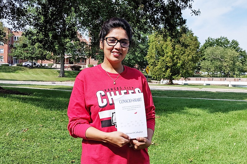 Miriam O'Callaghan, assistant professor of management at William Woods University, holds her new book "Conscio-Smart." The book aims to prepare new generations of workers to succeed in the workforce.