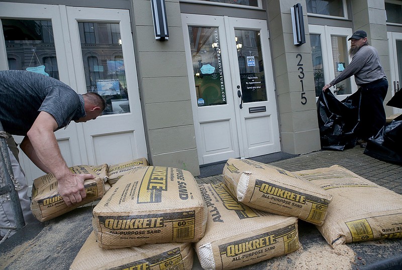Jeremy Franklin, left, with Mitchell Historic Properties, unloads bags of sand Tuesday, Sept. 17, 2019, at Texas Scuba Adventures in Galveston, Texas. He and Chad Sterns were preparing for possible flooding from Tropical Storm Imelda.