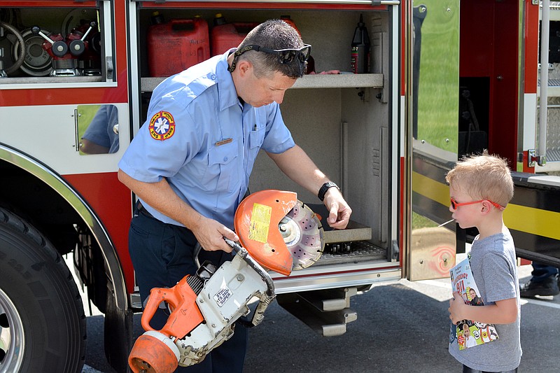 Firefighter Michael Bainbridge shows Aiden Dewey, 5, a metal saw at the 2018 Might Machines event at Capital Mall. The event will return to the Capital Mall parking lot on Saturday. Sally Ince/News Tribune