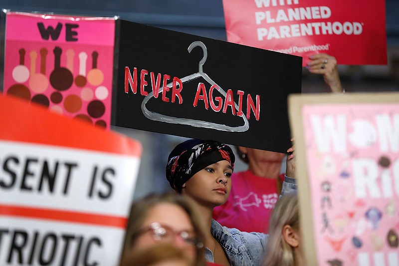 August Mulvihill, of Norwalk, Iowa, center, holds a sign during a rally May 21 to protest recent abortion bans at the Statehouse in Des Moines, Iowa. 