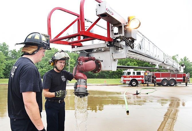 Firefigher trainee Derrick Coffelt, left, and Anthony Trapani look over the nozzle end of Reserve Ladder 1 during apparatus familiarization and pump training in June at the Hyde Park facility. As the city acquires new fire trucks, the old ones are then used as reserve fleet vehicles and kept at the mid-town training facility.