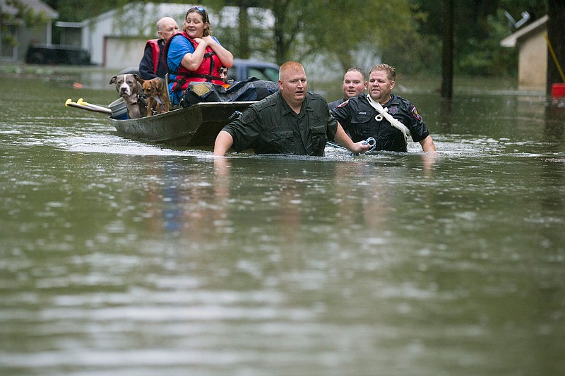 Splendora Police Lt. Troy Teller, left, Cpl. Jacob Rutherford and Mike Jones pull a boat carrying Anita McFadden and Fred Stewart from their flooded neighborhood inundated by rain from Tropical Depression Imelda on Thursday in Spendora, Texas.