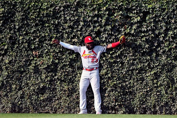 Cardinals left fielder Marcell Ozuna leans into the ivy after catching a fly ball hit by Kris Bryant of the Cubs to end the seventh inning of Friday afternoon's game in Chicago.