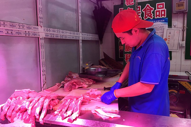 In this Wednesday, Sept. 11, 2019, photo, a butcher slices cuts of pork at a meat market in Beijing. China's government said Wednesday, Sept. 18, 2019, that is releasing pork from official stockpiles to ease a shortage and cool surging prices ahead of Oct. 1 celebrations of the Communist Party's 70th anniversary in power. (AP Photo/Fu Ting)