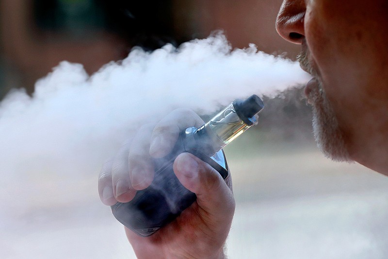 A man exhales Aug. 28 while smoking an e-cigarette in Portland, Maine. Walmart says it will stop selling electronic cigarettes at its namesake stores and Sam's Clubs following a string of illnesses and deaths related to vaping. The nation's largest retailer said Friday that it will complete its exit from e-cigarettes after selling through current inventory. It cited growing federal, state and local regulatory complexity regarding vaping products.