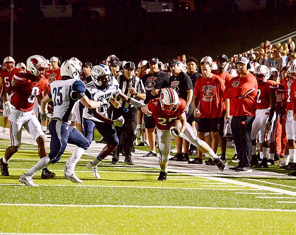Jefferson City's Nick Williams tries to stay in-bounds as he is being pursued by a pair of St. Louis University High defenders during Friday night's game at Adkins Stadium.