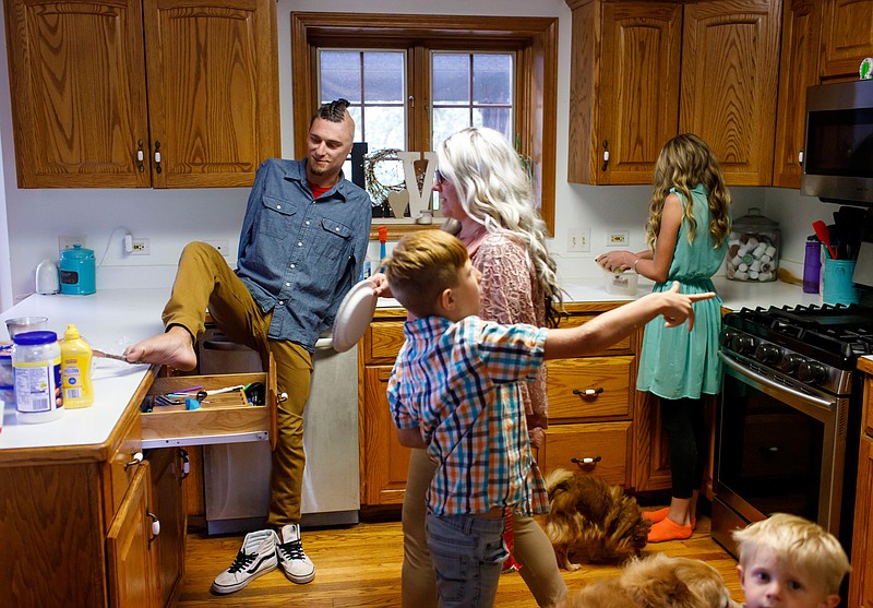 Jordan Zulauf pulls silverware out of the kitchen drawer as his aunt Jeanette Zulauf makes lunch for her children Dylan, 9, Delanney, 12, and Donovan, 2, on Wednesday, Aug. 21, 2019 at their West Chicago home. In 2016, Comcast subcontractor Robert Zulauf died after being electrocuted and his nephew Jordan lost his arms in an incident with a power line. (Brian Cassella/Chicago Tribune/TNS) 