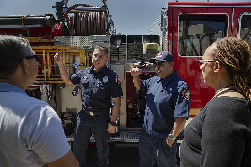 In this photo taken June 9, 2019, Los Angeles County firefighter Salvador Mejia, left, and Luis Gonzales, a Community Emergency Response Team instructor with the fire department, talk to CERT participants Berwyn Salazar and Frances Roberts in Carson, Calif. CERT training teaches members of the public how to begin helping their neighbors before professional first responders can arrive on scene. As police and firefighter numbers dwindle, authorities urge personal responsibility. (Brigette Waltermire/News21 via AP)