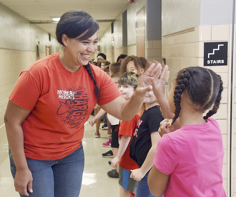 Chris Duren gives a student a high-five Thursday in the hallway at Moreau Heights Elementary School. Duren gives and receives numerous high-fives and hugs while walking the hallway. 
