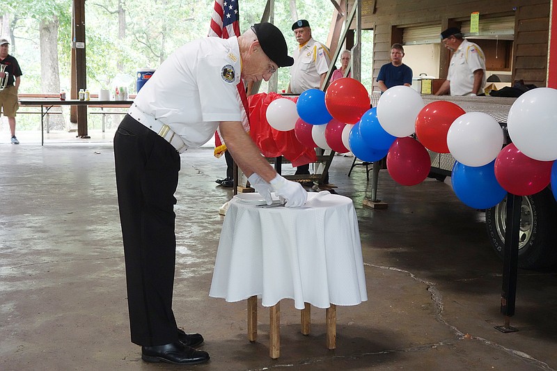 Veteran Gary Miller, with the VFW Post 1003, sets a plate and silverware on a table during the POW/MIA ceremony at Sunday's Veterans Appreciation in the Park. The prisoner of war, missing in action memorial table is a ceremonial remembrance to honor the memory of those missing in action or prisoner of war military service members.