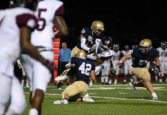 Helias teammates Drew Higgins (11) and Ethan Holzhauser (42) go high and low to tackle Cardinal Ritter wide receiver Luther Burden during last Saturday night's game at Ray Hentges Stadium.