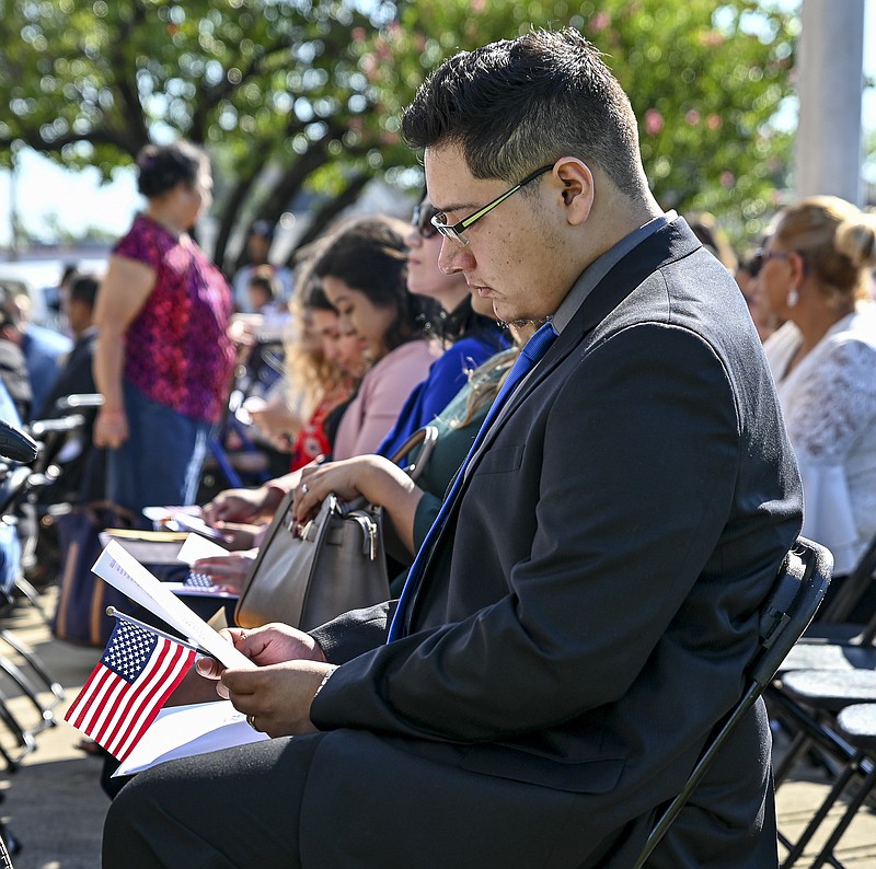 Kevin Gomez, 20, from Guerrero, Mexico, sits in his reserved seat and reads the "Star Spangled Banner," at U.S. Citizenship and Immigrations Services' Naturalization Ceremony at the federal courthouse on Friday, September 27, 2019, in Texarkana. Friday. The federal districts of Arkansas and Texas conducted a joint naturalization ceremony at the courthouse to initiate new American citizens from other countries.