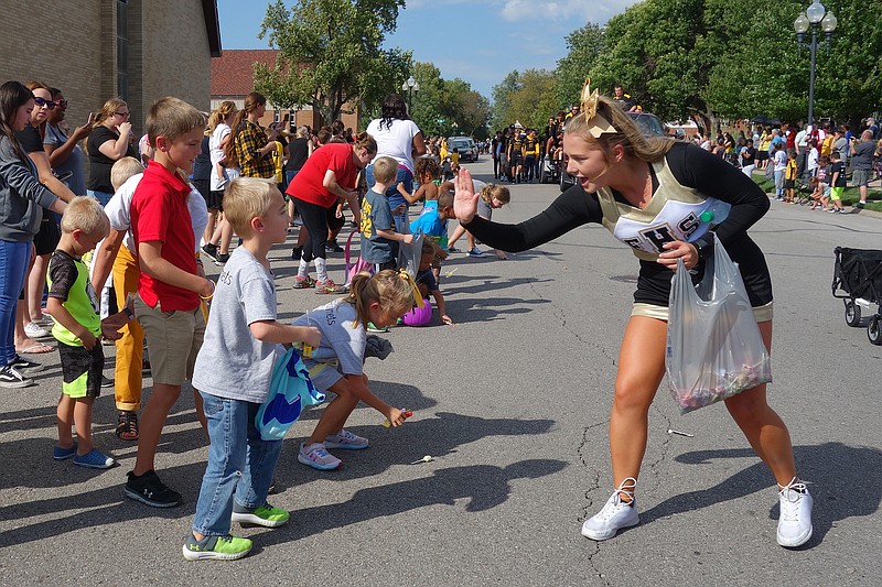Fulton High School 
cheerleader Olivia Gowin, right, goes in for a high-five during Friday's homecoming parade. Crowds of children lined Court Street to cheer and pick up candy. 
