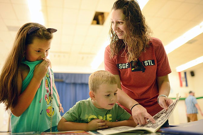 Joni Bond points out a photo of herself to her children Jovi, 7, and Hunter, 4, on Saturday from an old yearbook during a 50th anniversary celebration at Cedar Hill Elementary School. The Bonds have three generations in their family who have attended the school. 