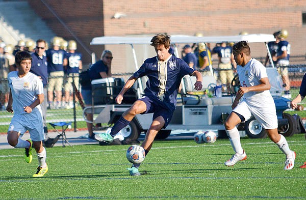 Luke Hynes of Helias dribbles the ball between a pair of Guadalupe Centers Charter players during Tuesday's game at the Crusader Athletic Complex.