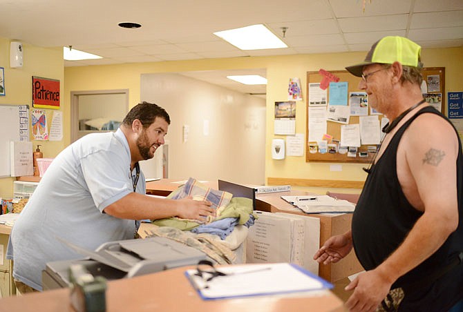 The Salvation Army Center of Hope Director Brian Vogeler gives Michael Johnson a set of clean sheets Wednesday at the shelter. Several people seeking shelter have reached out to Vogeler looking for a space but have been turned away because the center has almost consistently been at full capacity since the May 22 tornado.
