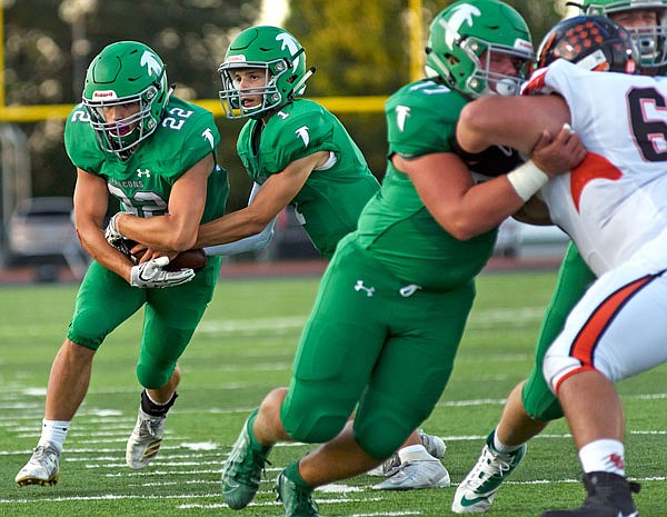 Blair Oaks quarterback Dylan Hair looks downfield while handing the ball off to running back Riley Lentz during a game earlier this season against Oak Grove at the Falcon Athletic Complex in Wardsville.