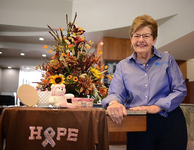 Rosie Verslues stands with a breast cancer awareness items Friday at Legends Bank. Verslues is a founder of the Encouragement Through Caring, a breast cancer survivor support group at Capital Region Medical Center's Goldschmidt Cancer Center.