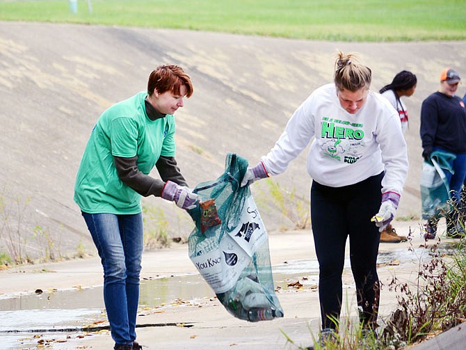 Petra Andrei, left, and Emma Haenchen collect trash Saturday from the concrete ditch that runs alongside The Linc and through the Lincoln University campus. The students, who are members of the Lincoln University Agriculture Club, gathered plastics and other man-made products but were careful to leave organic items, such as fallen branches or leaves, in their natural environment. 