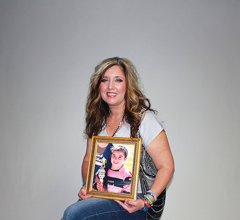 Michelle Cox holds a picture of her daughter Chloe Cox who started Chloe's Journey of Faith Foundation after she was diagnosed with terminal brain cancer.