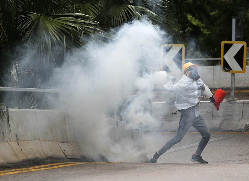 Protesters throw back tear gas at police in Hong Kong, Sunday, Oct. 6, 2019. Shouting "Wearing mask is not a crime," tens of thousands of protesters braved the rain Sunday to march in central Hong Kong as a court rejected a second legal attempt to block a mask ban aimed at quashing violence during four months of pro-democracy rallies. (AP Photo/Vincent Thian)