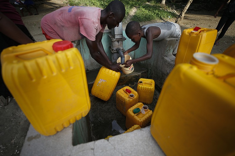 Residents pump drinking water from a well in the village of Barriere Jeudi, outside Leogane, Haiti, Saturday, Oct. 5, 2019. The political turmoil is hitting cities and towns outside the capital of Port-au-Prince especially hard, forcing non-government organizations to suspend aid as barricades ranging from large rocks to burning tires cut off the flow of goods between the city and the countryside, further deepening poverty in places like Leogane. (AP Photo/Rebecca Blackwell)