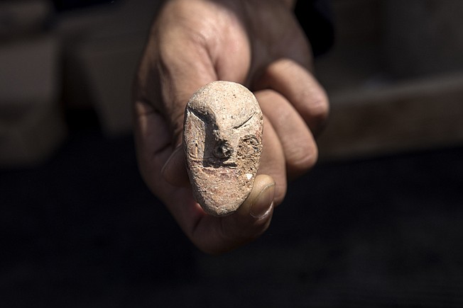 An archaeologist shows a figurine found at a large, 5,000-year-old city in northern Israel. 