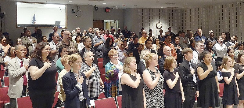 Sixty-four newly sworn-in U.S. citizens say the Pledge of Allegiance during a naturalization ceremony Monday at the Missouri National Guard Headquarters. The ceremony was presided over by U.S. District Judge Nanette Laughrey in the guard's auditorium.