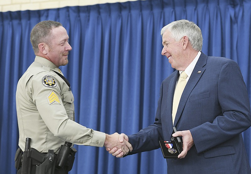 Gov. Mike Parson, right, thanks Stone County Sheriff Deputy Sgt. Shawn Fields for his service and presents him with the Medal of Valor Monday. Sandra Karsten read the report regarding Fields' acts of heroism during the Branson Duck boat disaster in which he risked his life to save people on the boat as it was sinking. Karsten is director of the Department of Public Safety and presided over the Missouri Public Safety Awards Ceremony at the MSHP academy gymnasium. Fields was among four recipients of this year's Medal of Valor. 