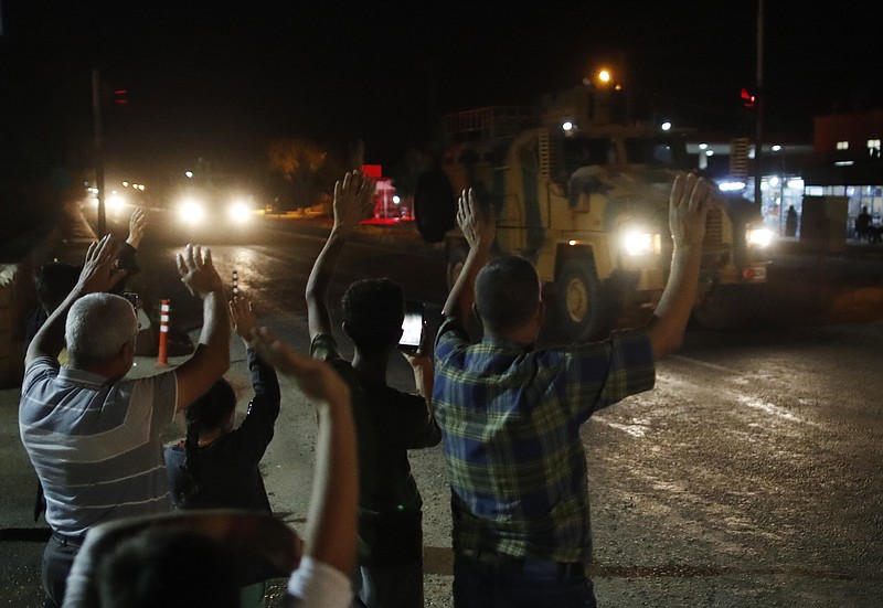 Local residents jeer and applaud as a convoy of Turkish forces vehicles and trucks carrying tanks and armoured personnel carriers driven in Sanliurfa province, southeastern Turkey, Tuesday, Oct. 8, 2019. The Turkey - Syria border has became a hot spot as Turkish Vice President Fuat Oktay said Turkey was intent on combatting the threat of Syrian Kurdish fighters across its border in Syria. (AP Photo/Lefteris Pitarakis)