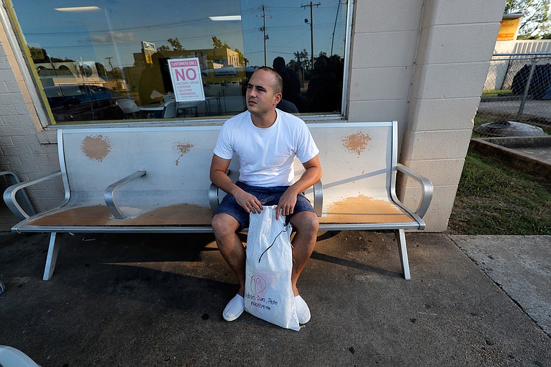 Pedro Cordoves Diaz, a 26-year-old from Cuba who was just released from the Winn Correctional Center, waits with his sole bag of belongings, at a bus station over 55 miles away, to travel to relatives in New Jersey, in Alexandria, La., Thursday, Sept. 26, 2019. He had been denied parole, but was ultimately given his release on $10,000 bond, paid by relatives in New Jersey. "I stayed in my bed waiting for the moment to leave to arrive," Diaz said. (AP Photo/Gerald Herbert)