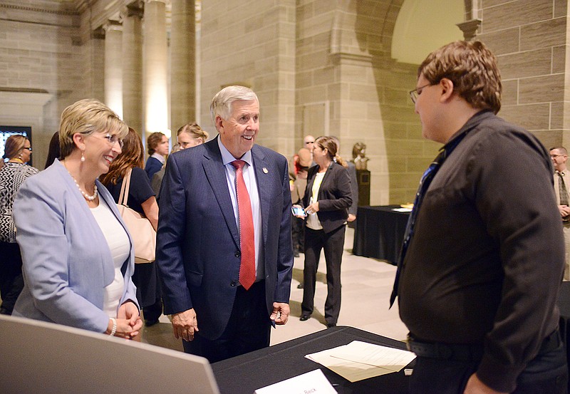 Thomas Beck, of Holts Summit, speaks with Gov. Mike Parson and Western Governors University Missouri's chancellor Angie Besendorfer on Thursday during a Model Employer Talent Showcase at the Capitol. The event served as a reverse job fair where applicants managed their own booths and provided information about their skillsets as they met with potential employers.